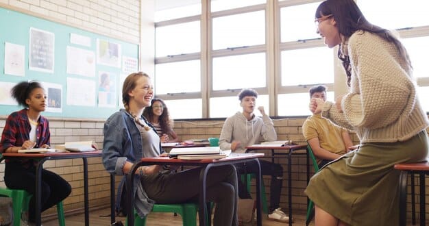 A teacher leading a classroom discussion with high school students. The students are actively engaged, asking questions and sharing their perspectives, highlighting the development of communication skills.